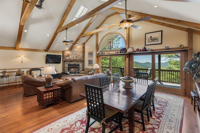 169 Heather View Ln, Sapphire, NC 28774 - dining area featuring ceiling fan, high vaulted ceiling, beamed ceiling, a stone fireplace, and wood finished floors