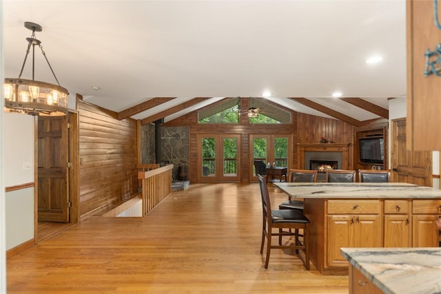 3398 Cullowhee Forest Rd, Cullowhee, NC 28723 - kitchen featuring a warm lit fireplace, open floor plan, wooden walls, light wood-style flooring, and a ceiling fan