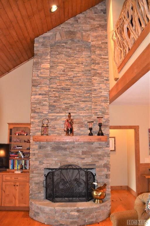 living room featuring a stone fireplace, wooden ceiling, high vaulted ceiling, and light hardwood / wood-style flooring