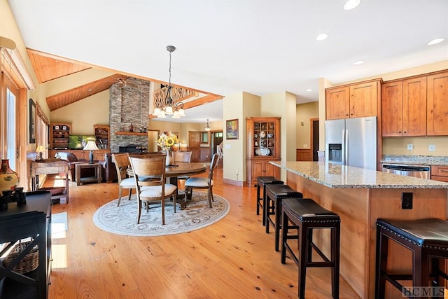 kitchen with pendant lighting, a breakfast bar area, stainless steel appliances, light stone countertops, and light wood-type flooring