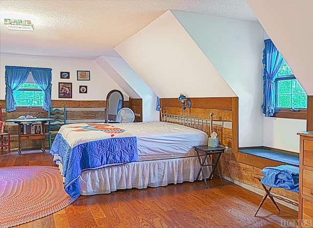 bedroom with a textured ceiling, hardwood / wood-style flooring, and vaulted ceiling