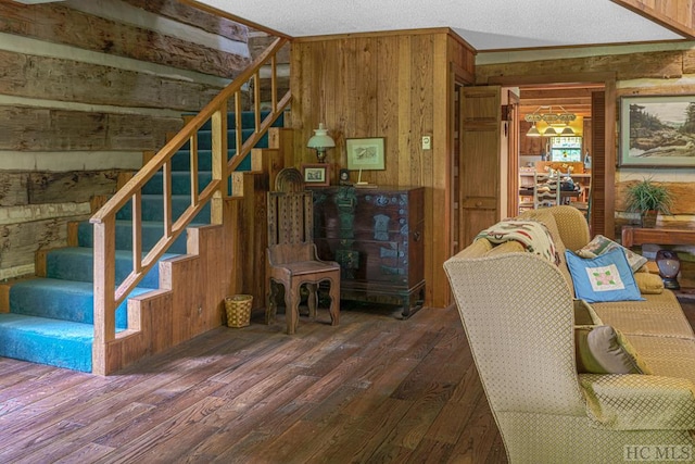 living room featuring dark wood-type flooring, wood walls, and a textured ceiling