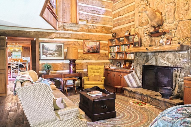 living room with hardwood / wood-style flooring, a towering ceiling, and a stone fireplace