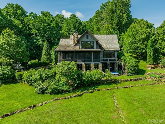 rear view of property with a lawn and a sunroom