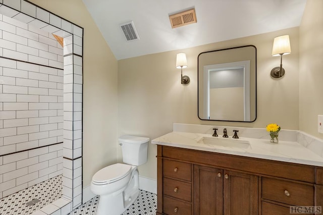 bathroom featuring vanity, vaulted ceiling, toilet, and tiled shower