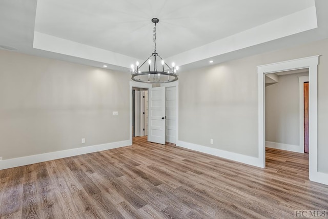 unfurnished dining area with hardwood / wood-style flooring and a raised ceiling