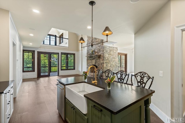 kitchen with pendant lighting, sink, green cabinets, a center island with sink, and stainless steel dishwasher