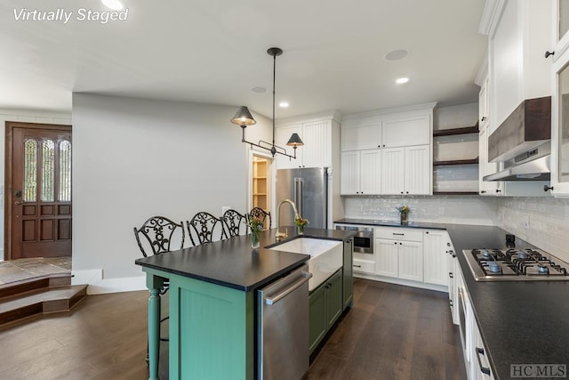 kitchen featuring a kitchen bar, white cabinetry, an island with sink, pendant lighting, and stainless steel appliances