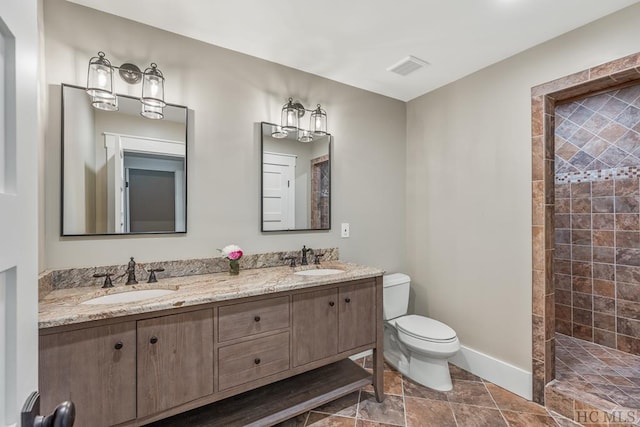 bathroom with vanity, tile patterned flooring, toilet, and a tile shower