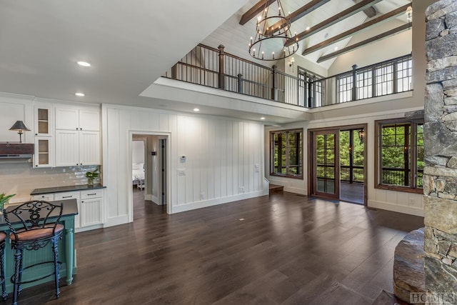 living room with beam ceiling, dark wood-type flooring, a chandelier, and high vaulted ceiling