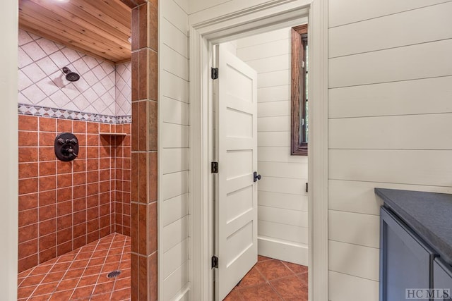 bathroom featuring tile patterned flooring, a tile shower, and wooden ceiling