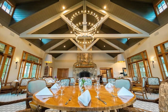 dining area with beam ceiling, high vaulted ceiling, a notable chandelier, a stone fireplace, and french doors