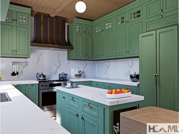 kitchen with green cabinets, stainless steel range with gas stovetop, backsplash, and exhaust hood