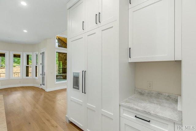 kitchen with light stone countertops, white cabinetry, and light hardwood / wood-style flooring