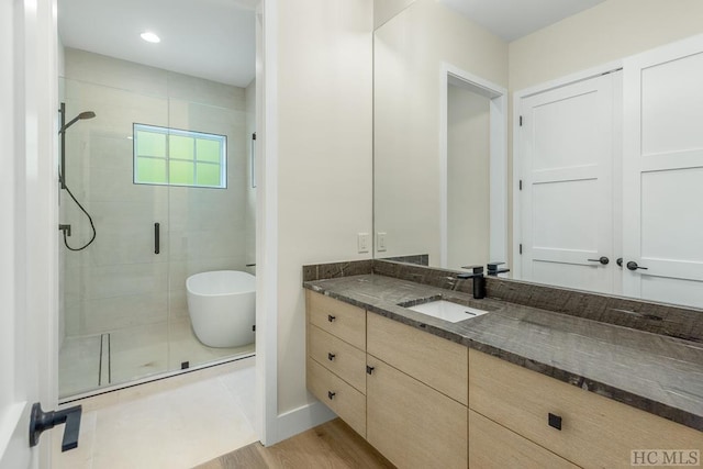 bathroom featuring independent shower and bath, hardwood / wood-style flooring, and vanity