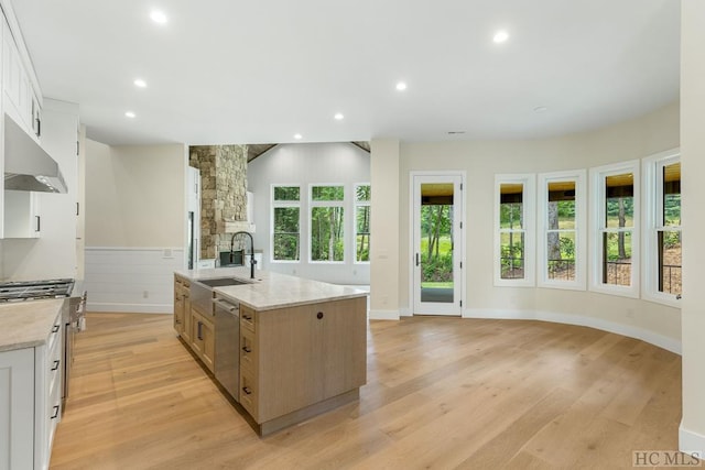 kitchen with light hardwood / wood-style floors, sink, white cabinets, and a spacious island