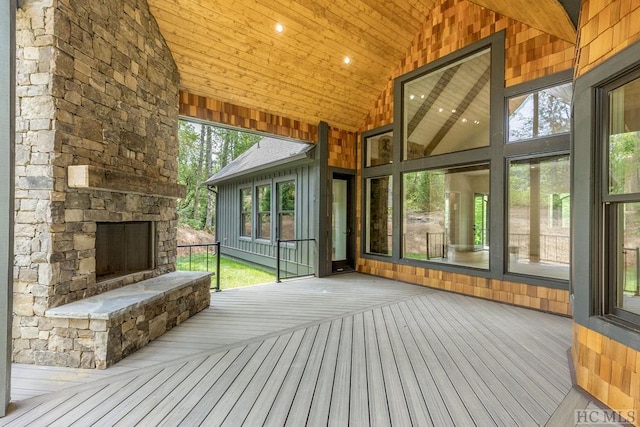 unfurnished sunroom with an outdoor stone fireplace, lofted ceiling, and a healthy amount of sunlight