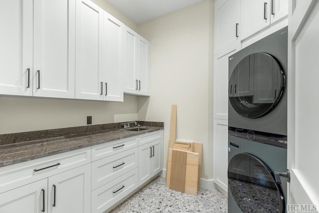 laundry room with cabinets, stacked washer and clothes dryer, and sink