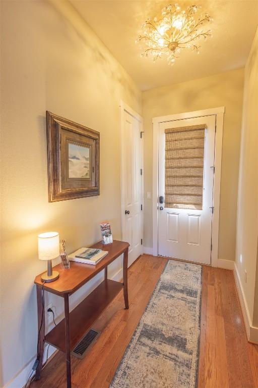 entrance foyer with a notable chandelier, baseboards, visible vents, and light wood finished floors