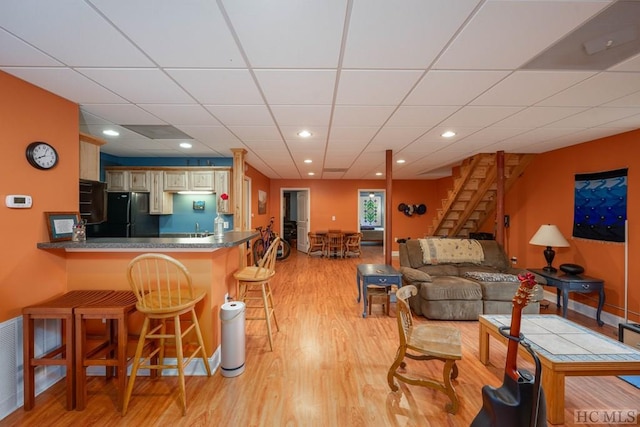 living room with light hardwood / wood-style flooring, sink, and a paneled ceiling