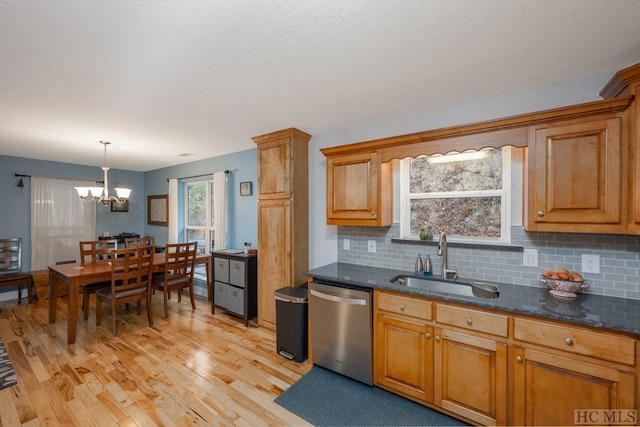 kitchen featuring sink, stainless steel dishwasher, pendant lighting, light hardwood / wood-style floors, and decorative backsplash