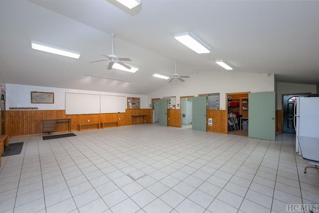 interior space featuring wooden walls, ceiling fan, light tile patterned floors, and lofted ceiling