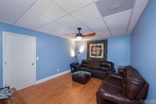 living room featuring ceiling fan, wood-type flooring, and a drop ceiling