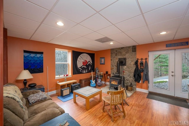 living room featuring a paneled ceiling, a wood stove, french doors, and hardwood / wood-style floors