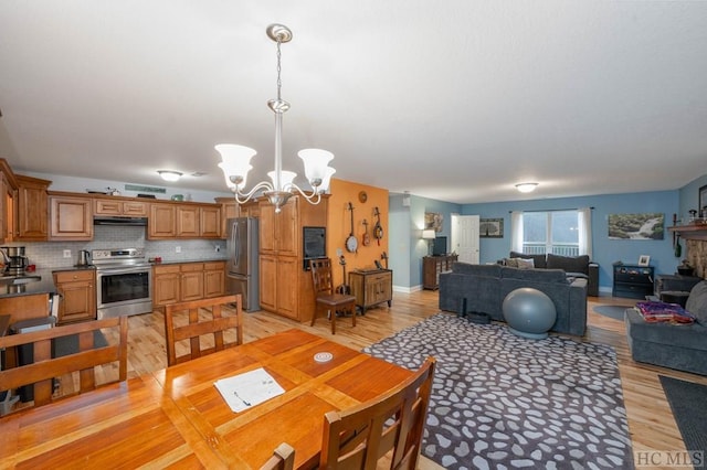 dining space with an inviting chandelier, sink, and light hardwood / wood-style flooring