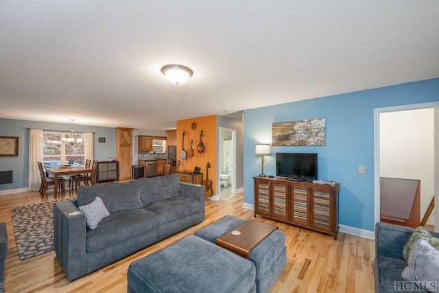 living room featuring light hardwood / wood-style flooring, a textured ceiling, and a notable chandelier