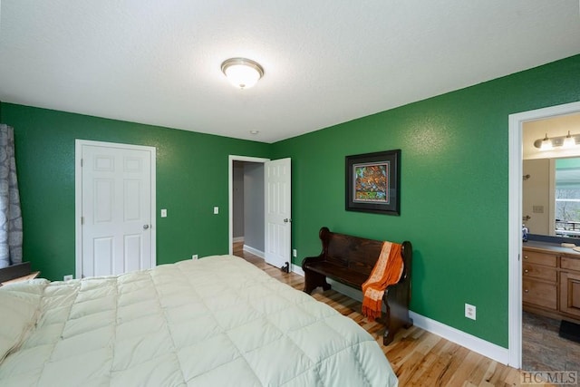 bedroom featuring connected bathroom and light hardwood / wood-style flooring