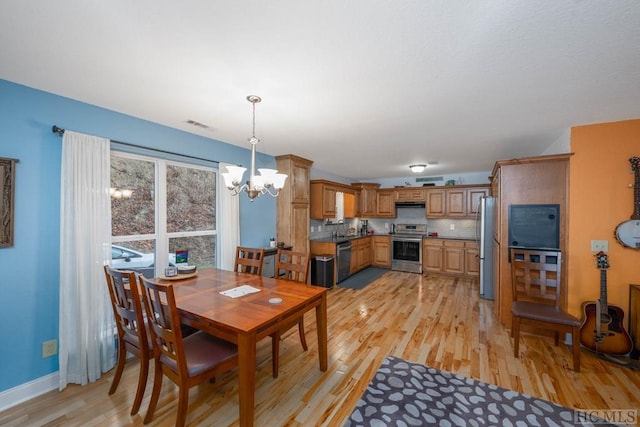 dining space with light hardwood / wood-style floors and a notable chandelier