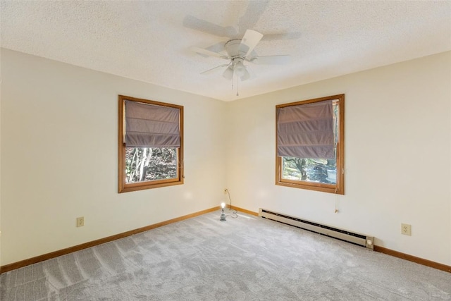carpeted spare room featuring a healthy amount of sunlight, baseboards, a ceiling fan, and a baseboard heating unit