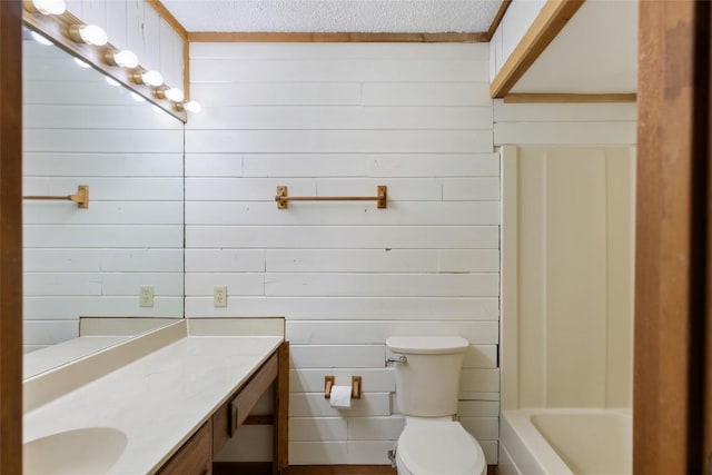 bathroom with a tub, vanity, toilet, and a textured ceiling