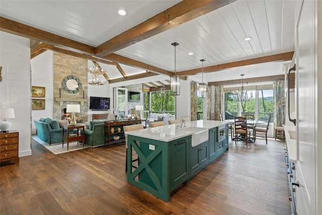 kitchen with a sink, green cabinetry, an inviting chandelier, and beam ceiling