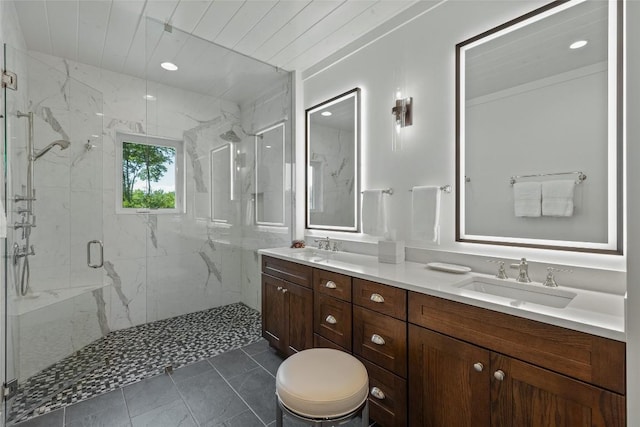 full bathroom with a sink, a marble finish shower, and double vanity