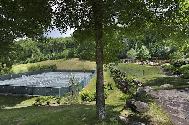 exterior space featuring a view of trees, fence, a yard, and a tennis court