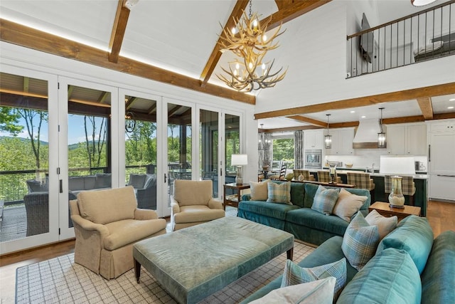 living area featuring beamed ceiling, a notable chandelier, light wood-style flooring, and high vaulted ceiling