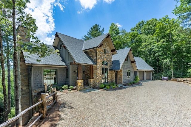 view of front of property featuring a chimney, a shingled roof, a garage, and stone siding