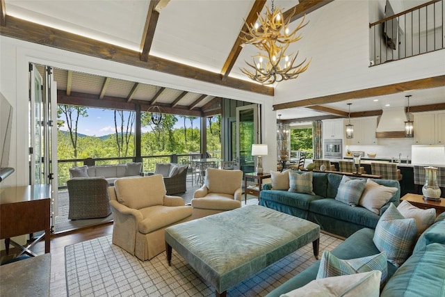 living area featuring lofted ceiling with beams, an inviting chandelier, and light wood finished floors