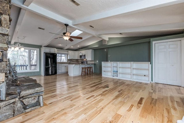 living room featuring light wood-style floors, visible vents, and lofted ceiling with beams