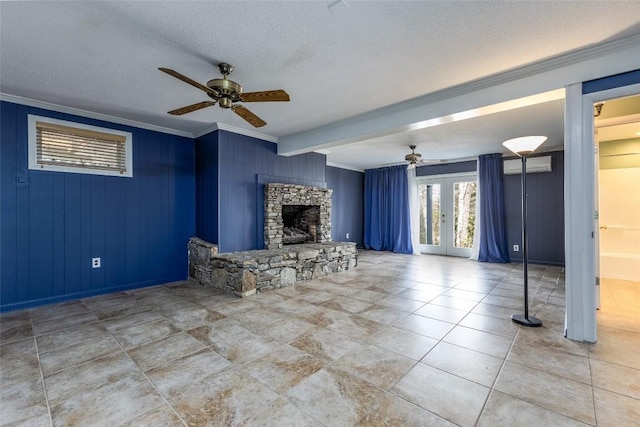 tiled living room featuring french doors, ornamental molding, an AC wall unit, a textured ceiling, and a stone fireplace