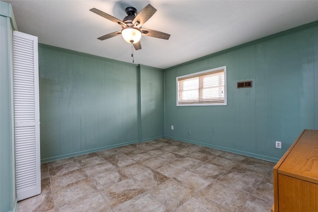 unfurnished room featuring ceiling fan, ornamental molding, visible vents, and baseboards