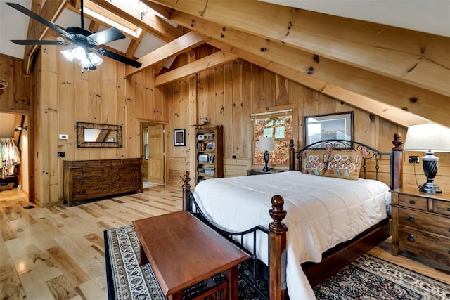 bedroom featuring wood walls, a skylight, beam ceiling, and light wood-style floors