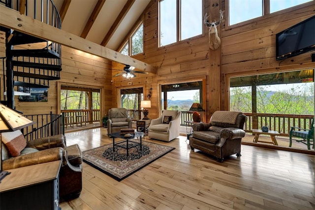 living area with wooden walls, high vaulted ceiling, and plenty of natural light