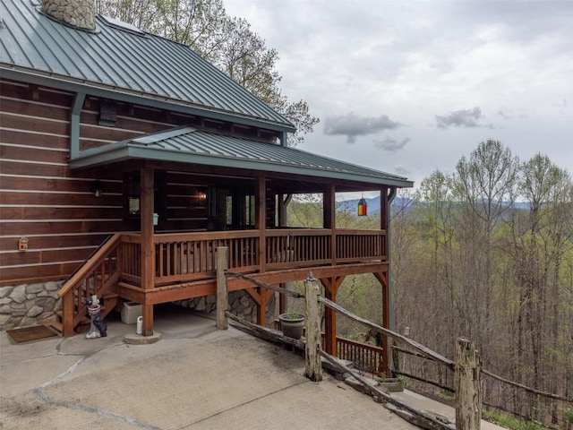 rear view of house with central air condition unit, a chimney, a standing seam roof, and metal roof