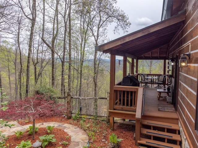 wooden terrace with outdoor dining space and a forest view