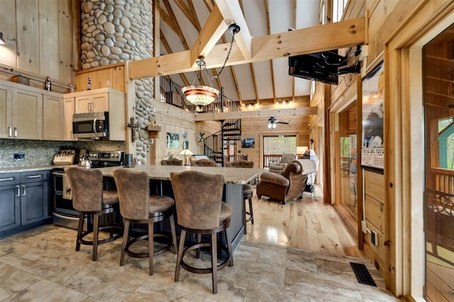 kitchen featuring high vaulted ceiling, visible vents, appliances with stainless steel finishes, wood walls, and open floor plan