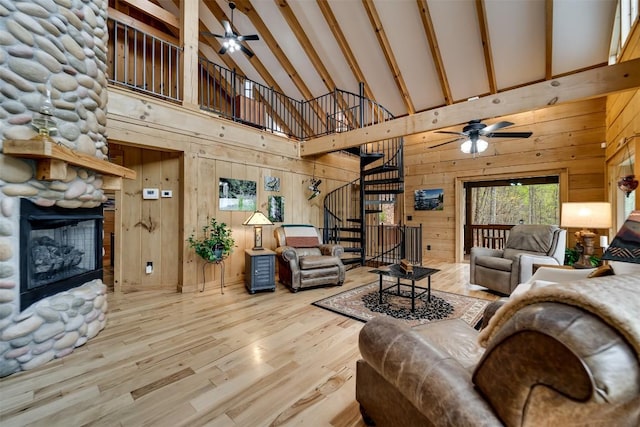living area featuring high vaulted ceiling, stairs, a fireplace, and a ceiling fan