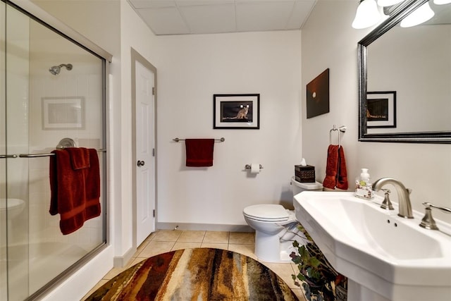 bathroom with a shower stall, a sink, tile patterned flooring, and toilet